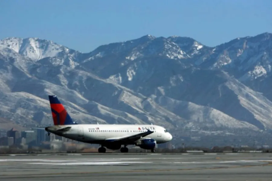 A plane on the runway at Salt Lake City airport with snowy mountains behind