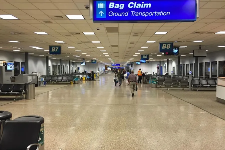 An airport corridor with overhead signs pointing to baggage claim
