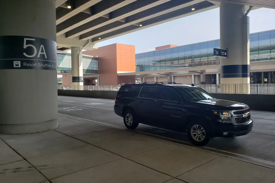 The passenger pickup curb at SLC airport, with a black SUV waiting by the numbered pillars